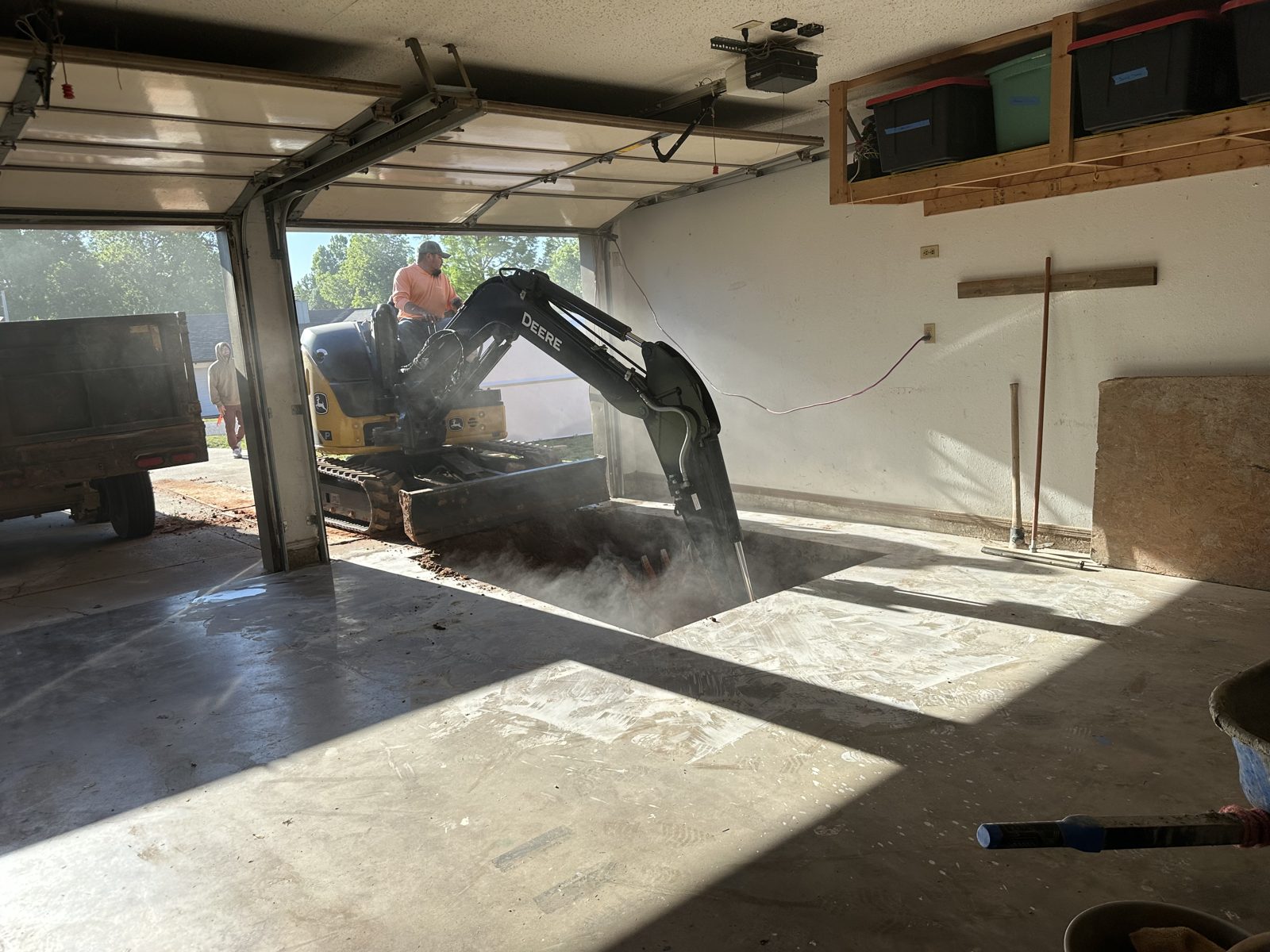 Mini excavator breaking out a garage slab for a storm shelter in East Texas