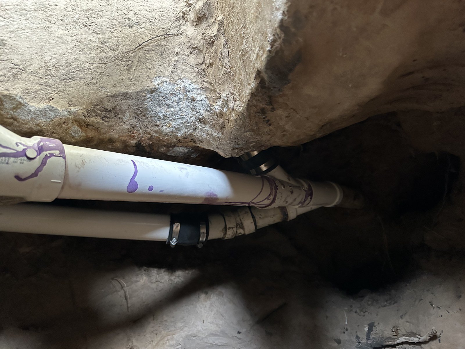New PVC drain line installed under a house