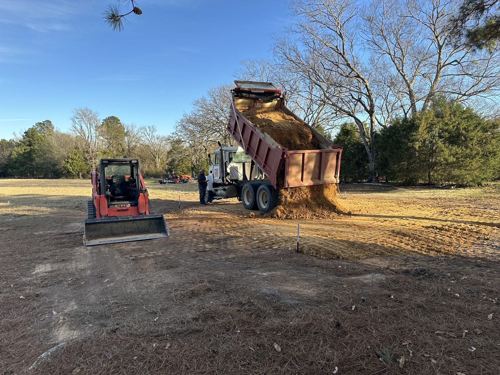 Dump truck spreading fill dirt for a pole barn pad in East Texas