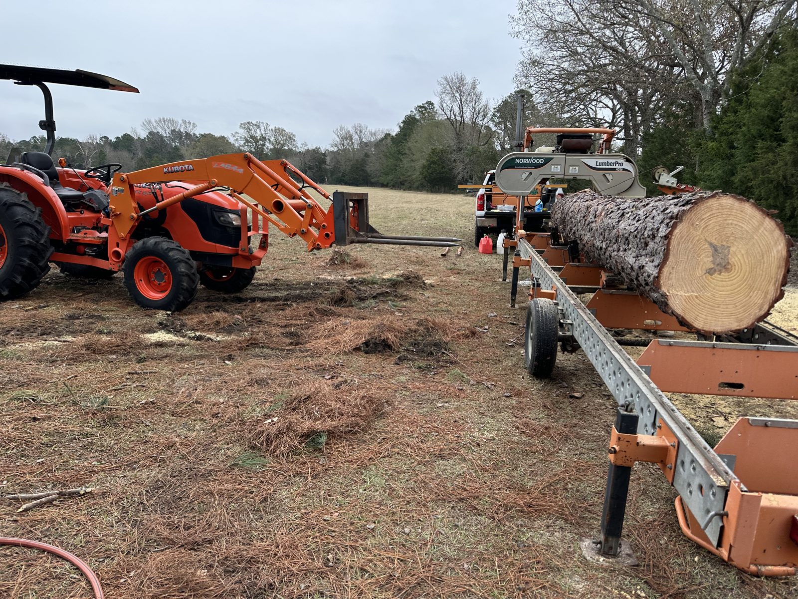 Tractor loading a log onto a portable sawmill in East Texas