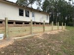 New wood retaining wall below a frame house in Pine Mills, Texas