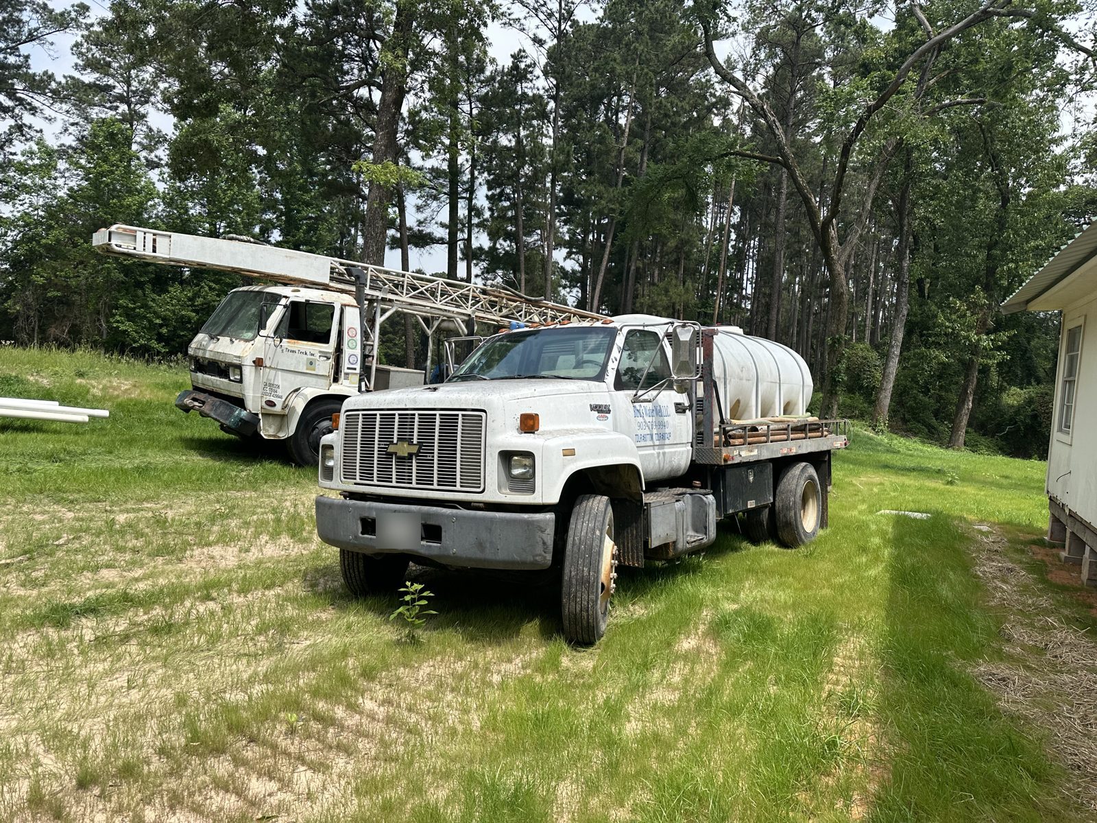 Water truck and drilling rig on a rural property in Pine Mills, Texas